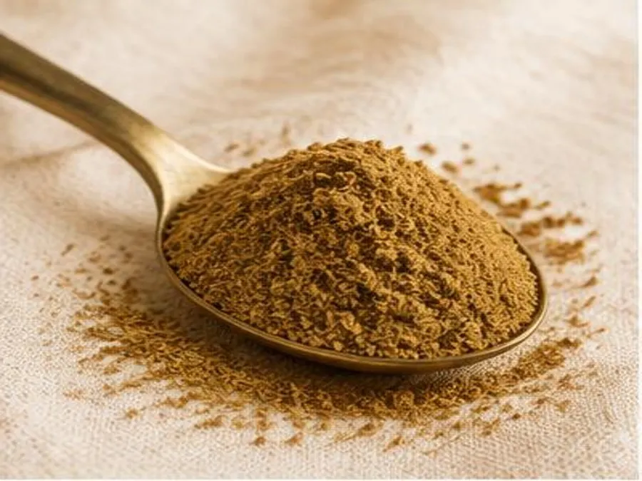 Cumin moulu dans une cuillère en laiton sur un linge crème